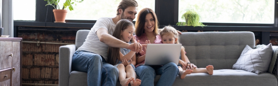 Familia de mamá, papá e hijos viendo su computador portatil en la sala de su casa