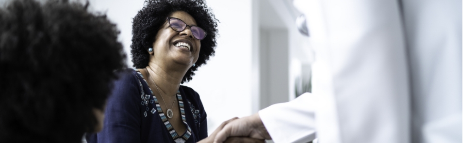 Mujer sonriente dando la mano al doctor para saludarlo