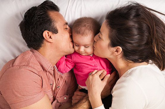 Mamá y papá besando al bebé